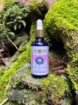 Bottle of Inoint elixir oil on a mossy rock with a natural background