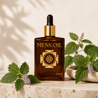 Bottle of 'Mens Oil' with a dropper on a stone surface with green leaves.