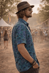Man wearing a patterned shirt and hat at a music festival