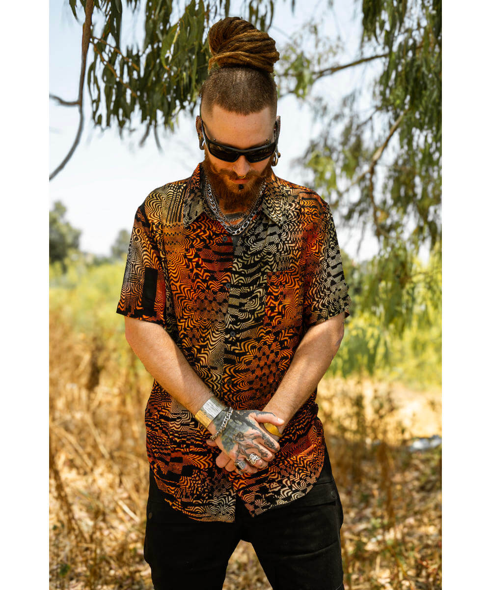 Man wearing a patterned shirt and sunglasses outdoors with trees in the background