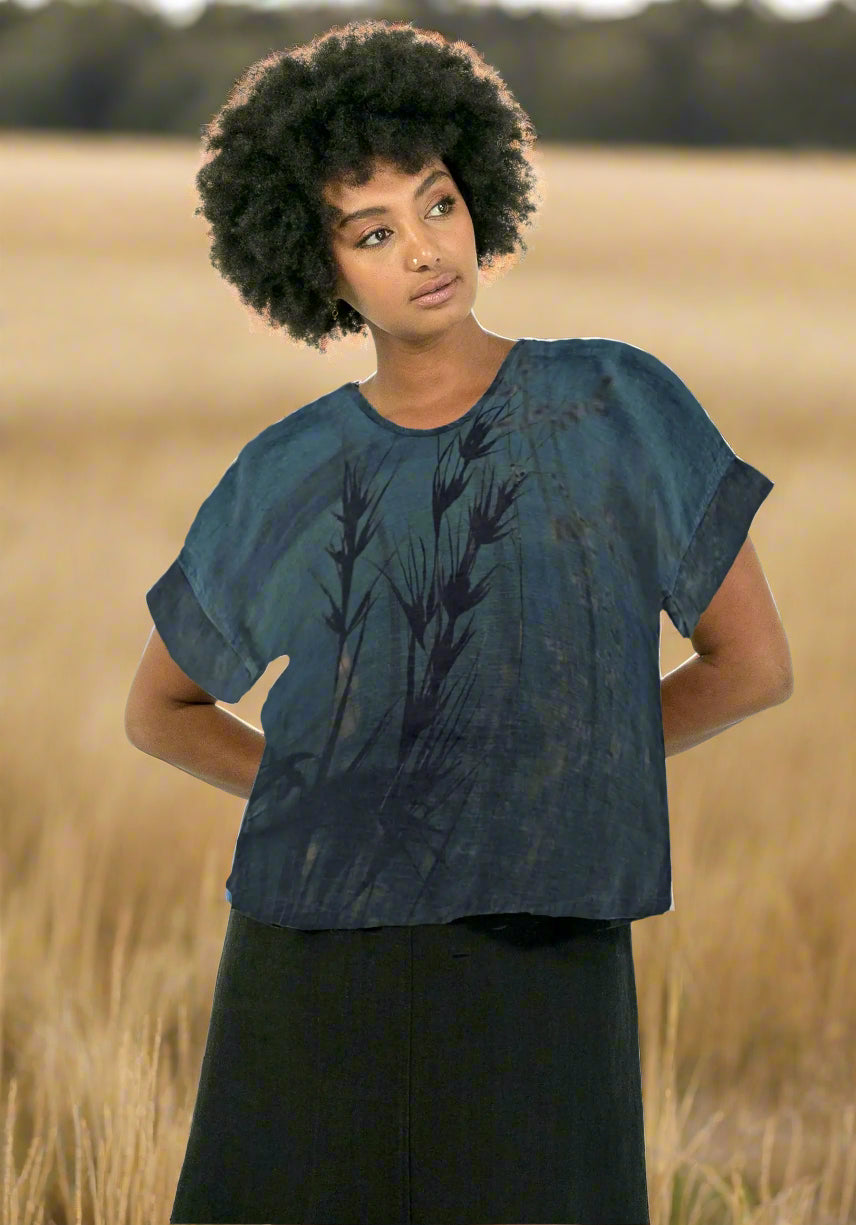Woman wearing a blue patterned top and black pants on a white background