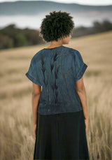 Person wearing a blue patterned top and black skirt on a white background