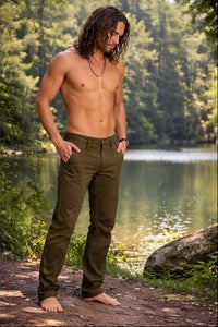 Man standing shirtless by a lake with trees in the background