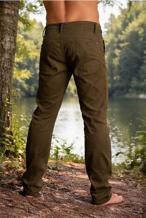 Person wearing olive green pants standing in a forest by a lake