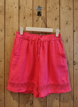 coral shorts hanging against a wall