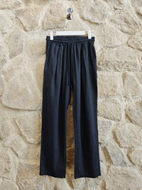 Black pants hanging on a hook against a stone wall