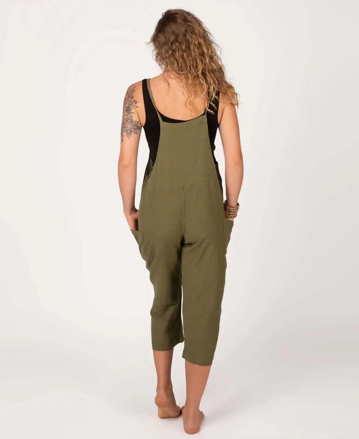 Person wearing a green jumpsuit with a black top on a white background