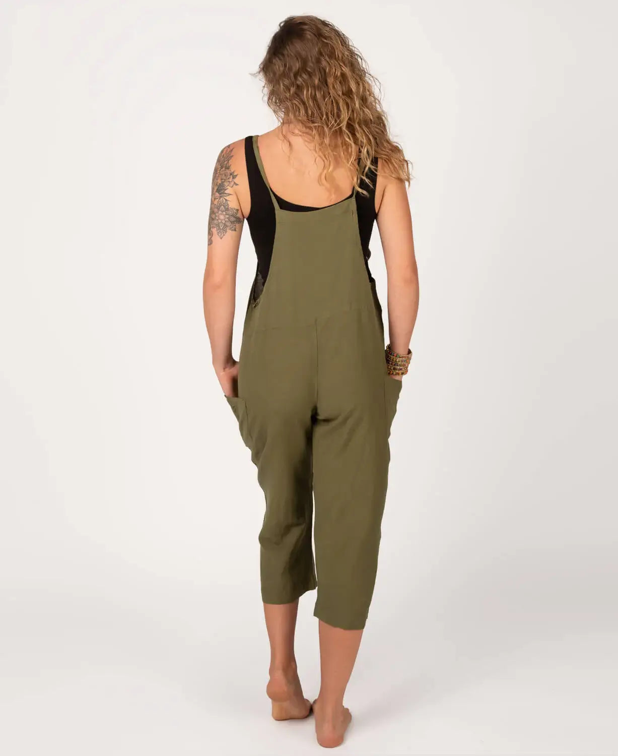 Person wearing a green jumpsuit with a black top on a white background