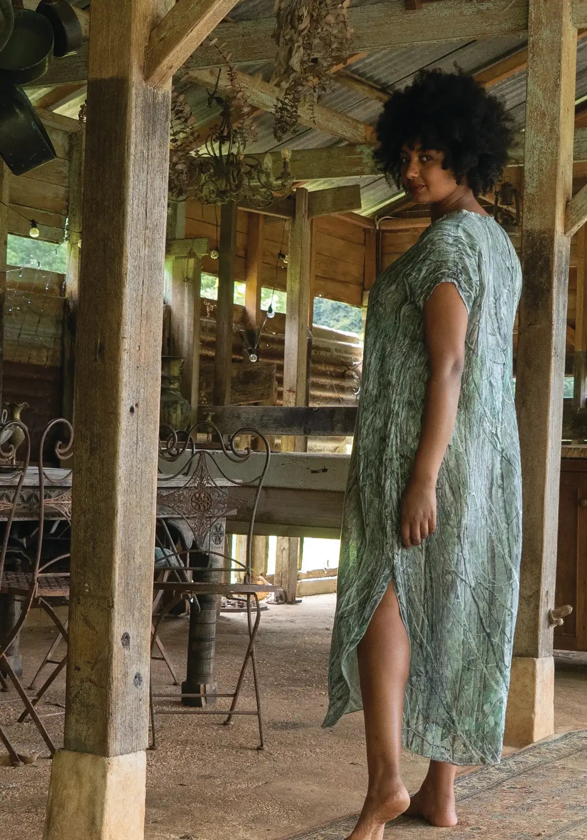 Woman in a green dress standing in a rustic wooden building.