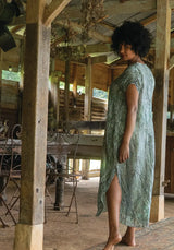 Woman in a green dress standing in a rustic wooden building.
