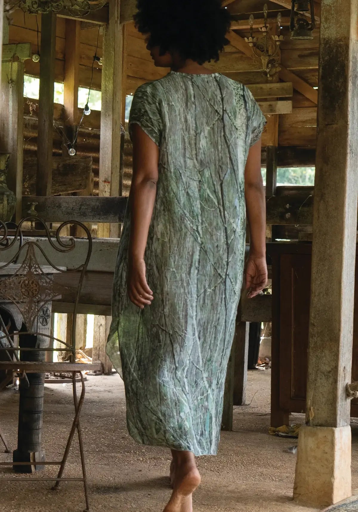 Person wearing a green patterned dress in a rustic indoor setting