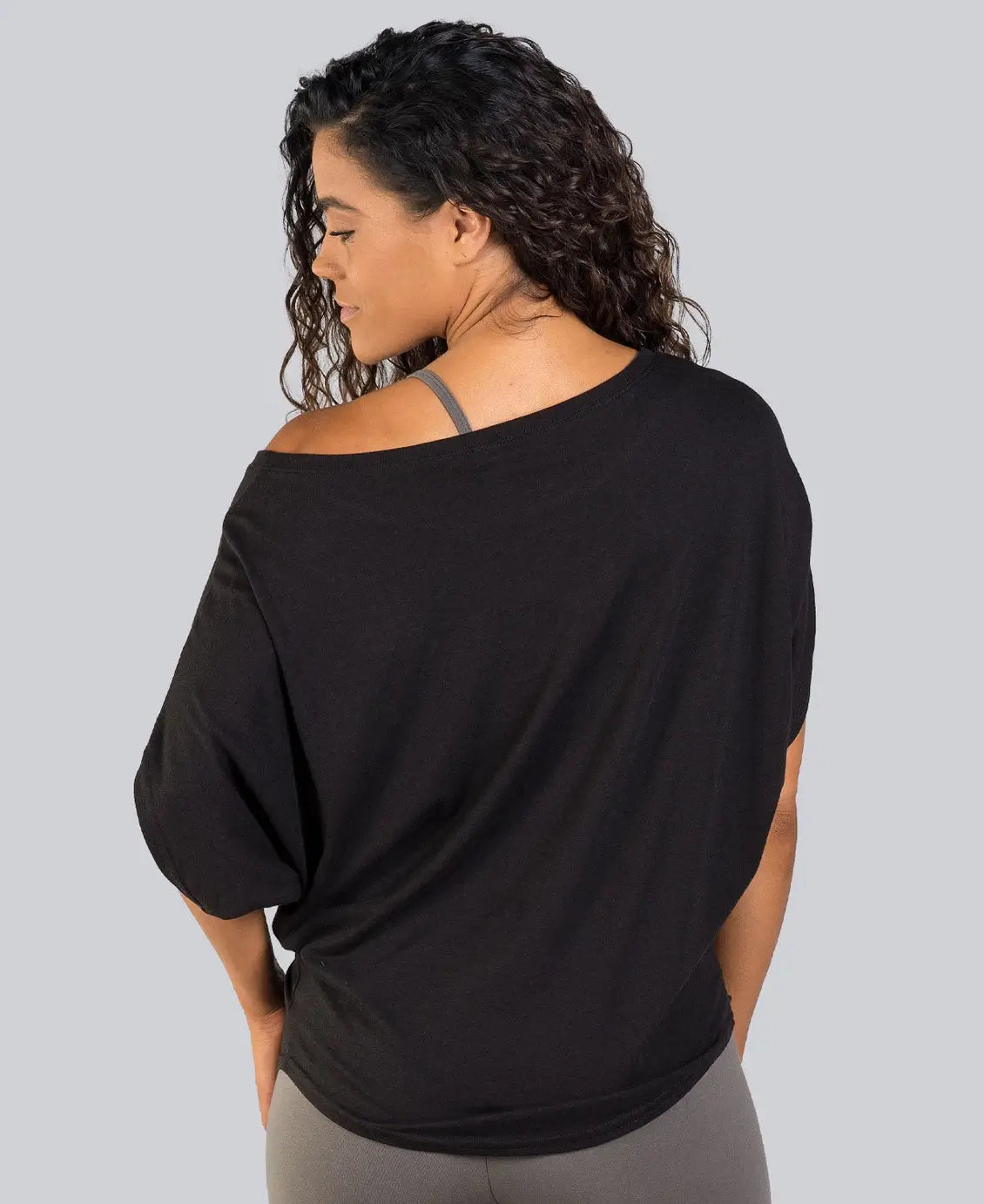 Woman wearing a black off-shoulder top on a gray background