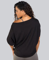 Woman wearing a black off-shoulder top on a gray background