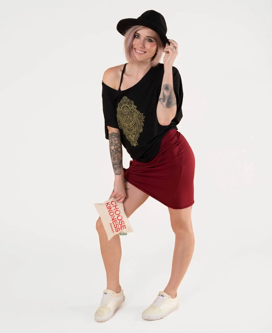 Woman wearing a black top with gold design and red skirt, holding a book, on a white background