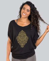 Woman wearing a black shirt with a gold mandala design on a gray background