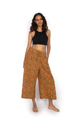 Woman wearing a black top and orange floral pants on a white background