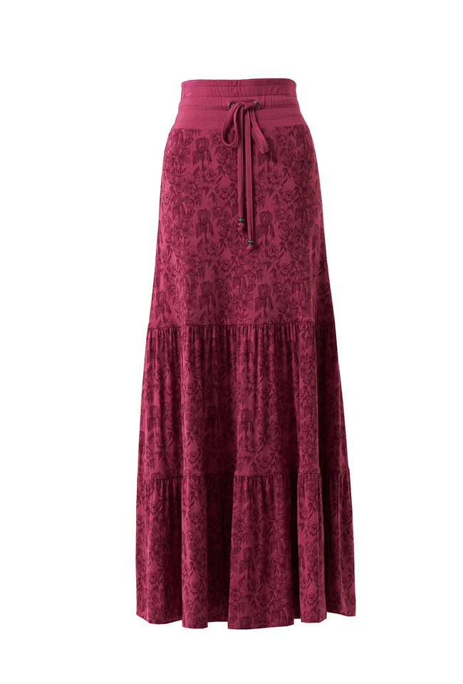 A tiered maxi skirt in a deep magenta-burgundy color with an intricate floral jacquard pattern, featuring a matching elastic waistband and drawstring.