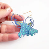 lady wearing earrings with peacock design 