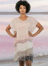 Woman wearing a light pink and gray gradient dress against a  pink salt lake background