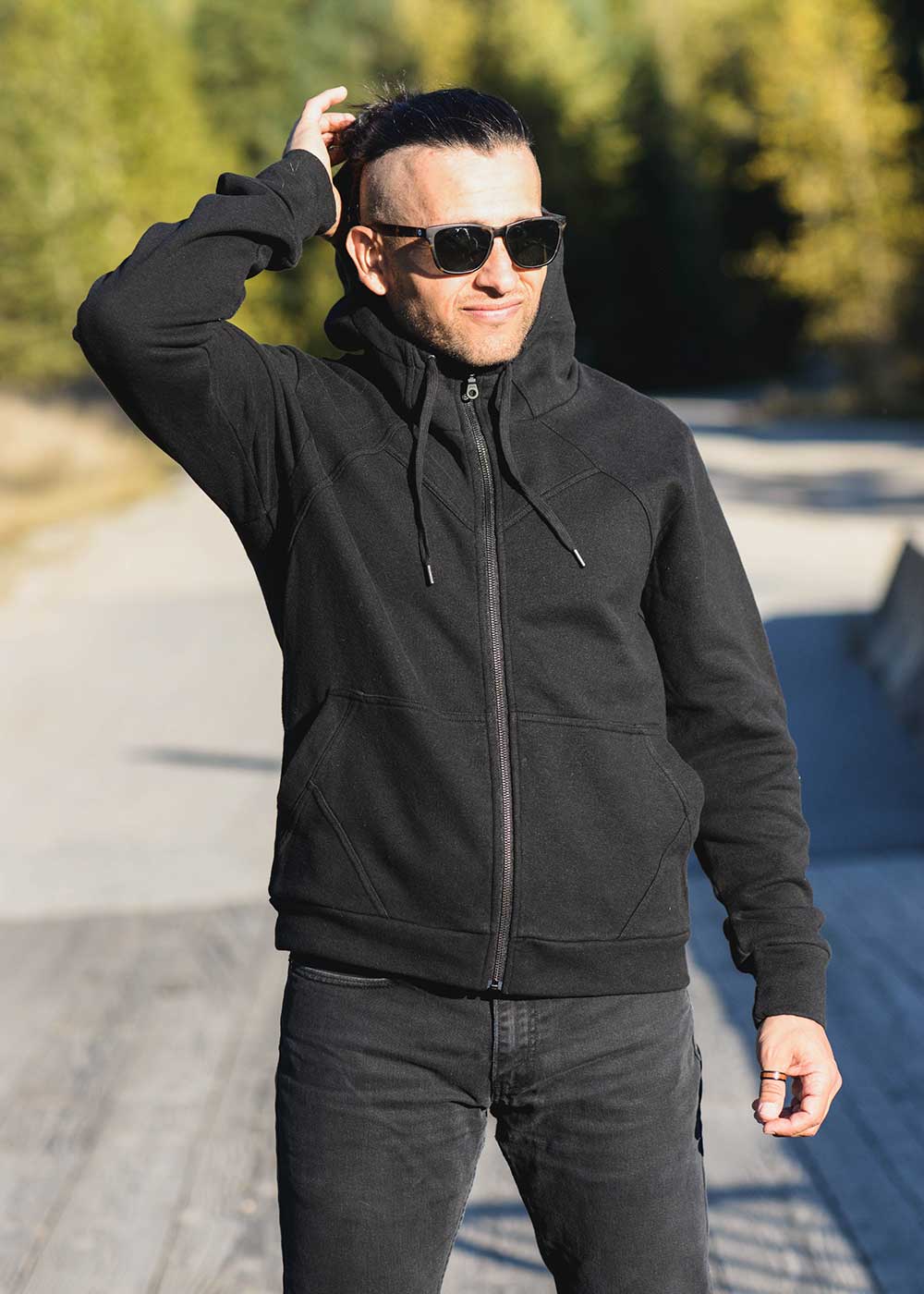Man wearing a black jacket and sunglasses outdoors
