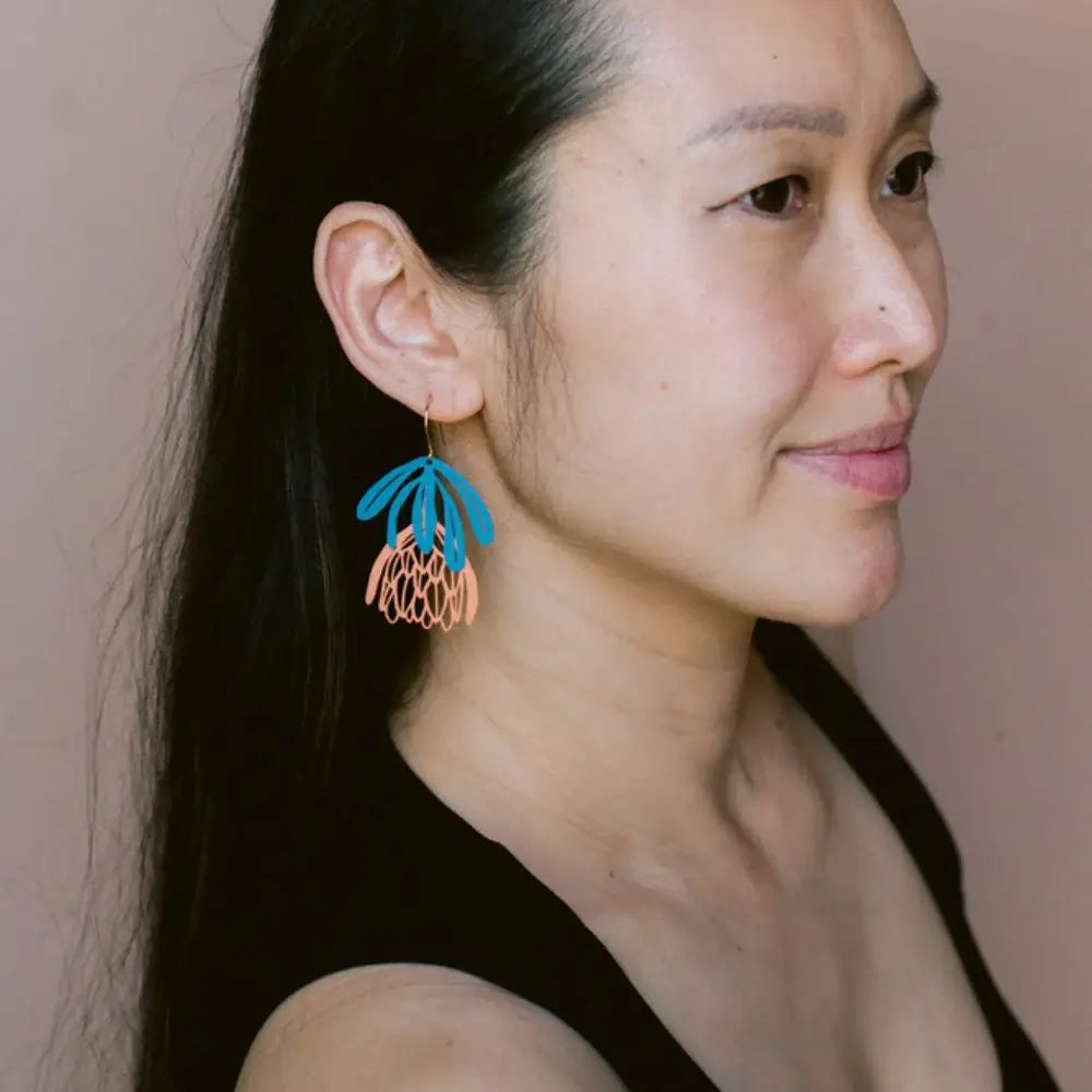 Woman wearing colorful earrings against a neutral background