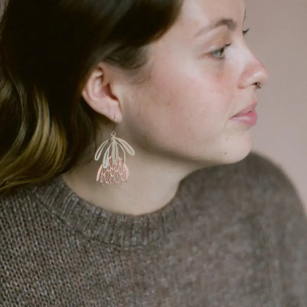 Close-up of a woman wearing a floral earring with a neutral background