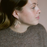 Close-up of a woman wearing a floral earring with a neutral background