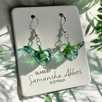 Green glass earrings on a card with 'Glass by Samantha Abbott Australia' text, against a natural background.