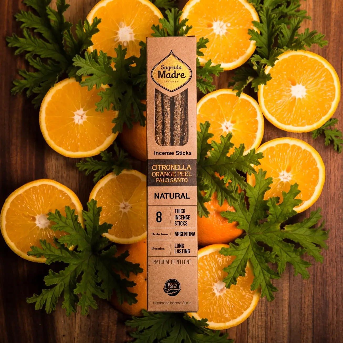 Box of Incense Sticks with Citronella, Orange Peel, and Palo Santo surrounded by sliced oranges and leaves on a wooden background.