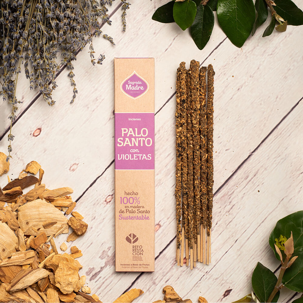 Palo Santo sticks with packaging on a wooden surface with herbs and leaves.