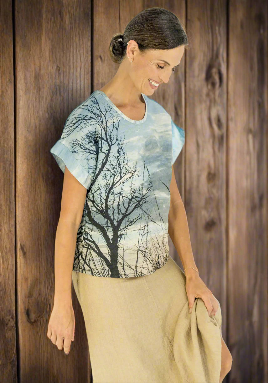 Woman wearing a t-shirt with a nature print against a plain background