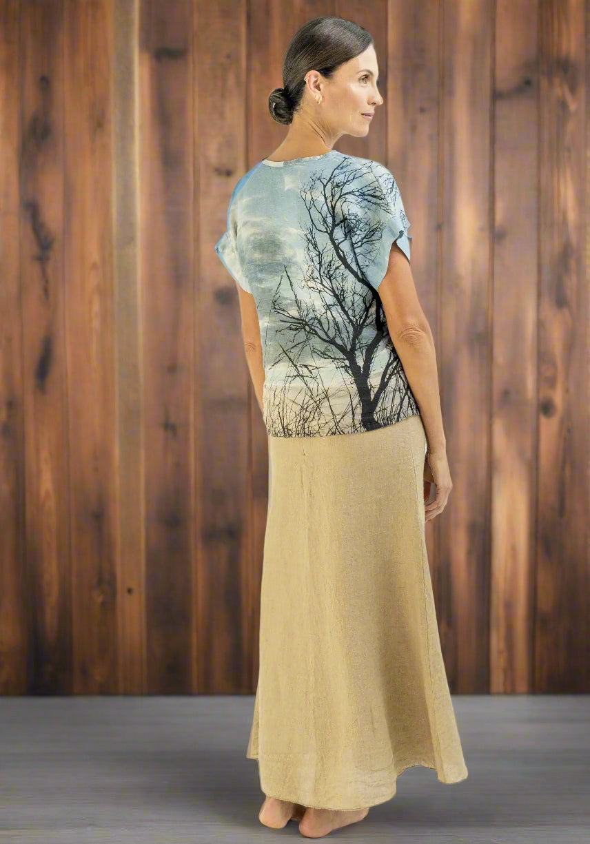 Woman wearing a t-shirt with a tree design and a beige skirt on a white background