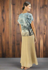 Woman wearing a t-shirt with a tree design and a beige skirt on a white background