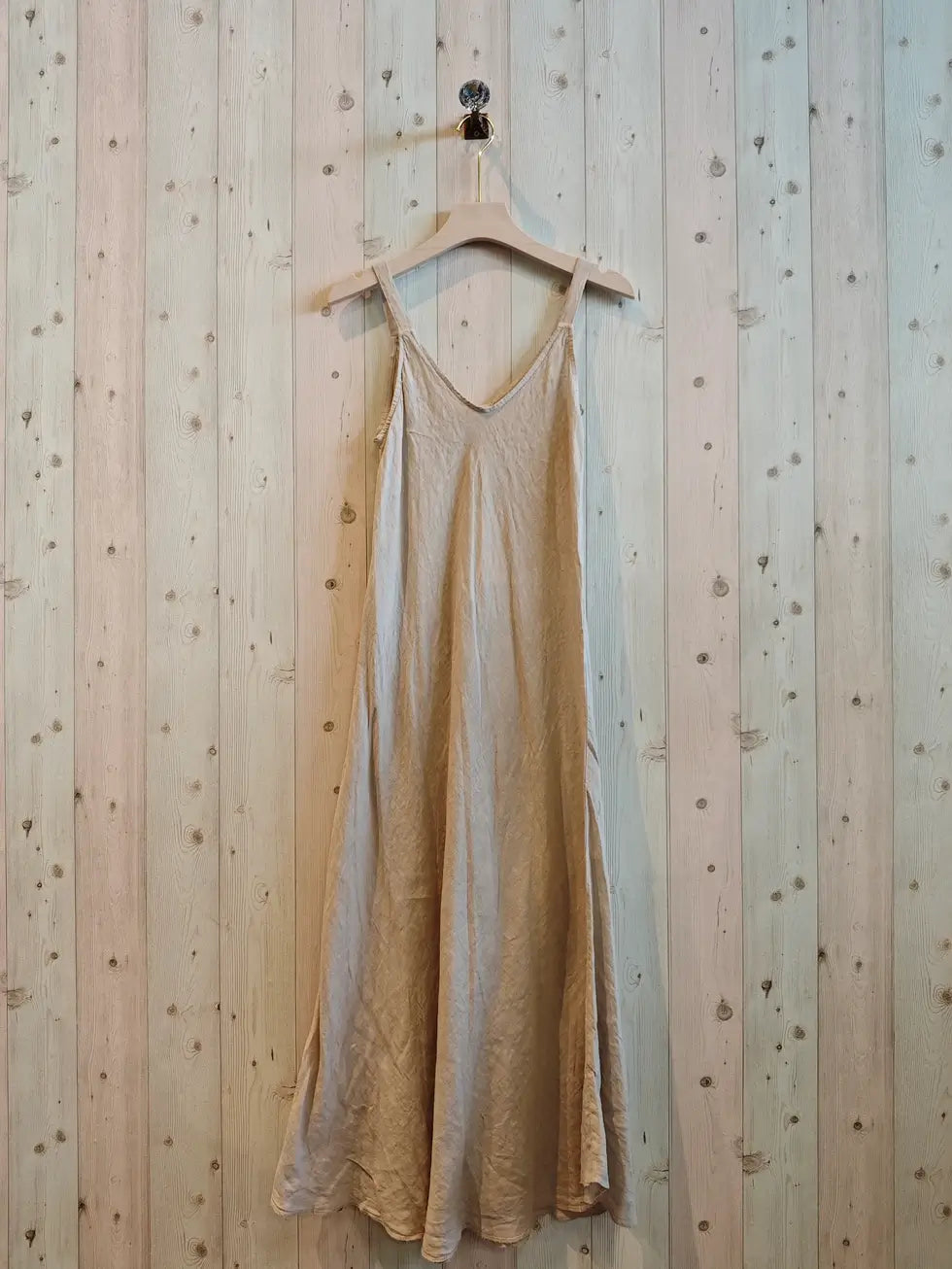 beige linen dress hanging against a wall
