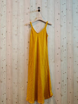 mustard colour dress on hanger against a wall

