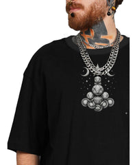 Person wearing a black t-shirt with a geometric design and multiple necklaces.