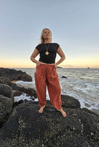 Back view of rust relaxed-fit unisex pants styled for a casual beach outfit