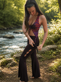 Woman in a colorful outfit standing by a stream in a forest