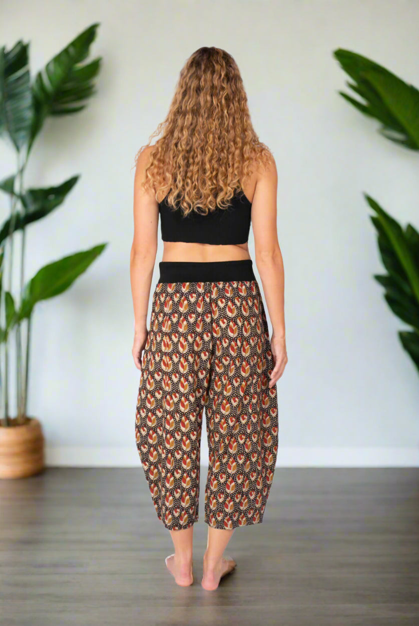 Woman wearing a black crop top and patterned pants on a white background