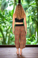 Person wearing a black crop top and patterned harem pants on a white background