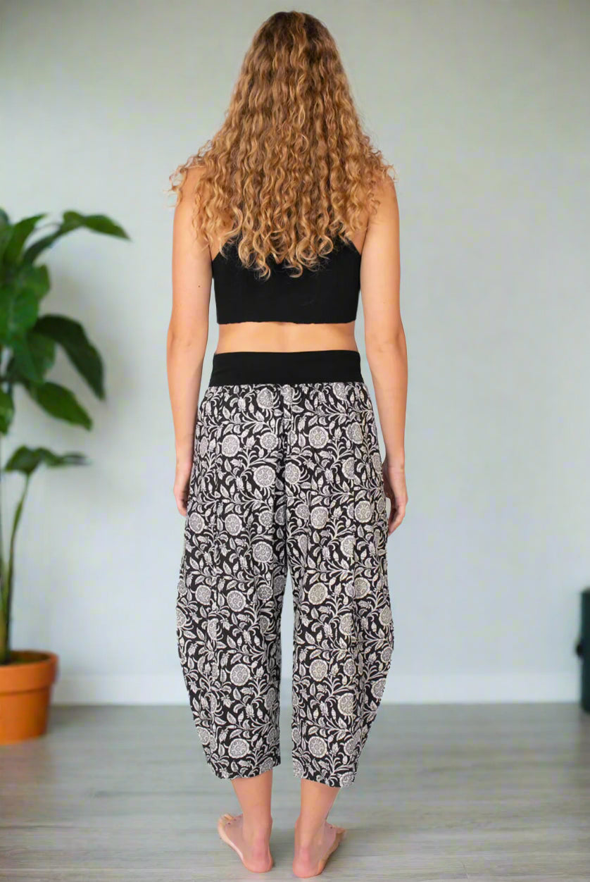Person wearing a black crop top and patterned pants on a white background