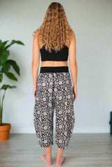 Person wearing a black crop top and patterned pants on a white background