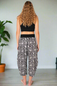 Person wearing a black crop top and patterned pants on a white background