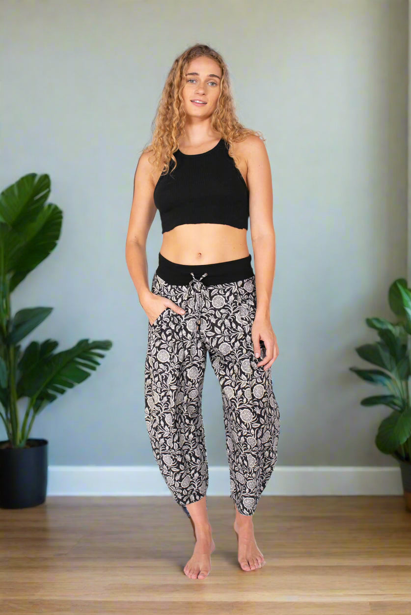 Woman wearing a black crop top and patterned pants on a white background