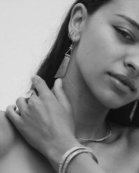 Close-up of a woman wearing earrings and a bracelet with a plain background