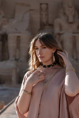 Woman in a pink dress standing in front of ancient stone statues.