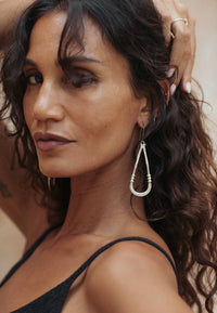 Shop Zuri Earrings in white brass with sterling silver hooks, featuring a long sculptural shape, hammered texture and lightweight feel.